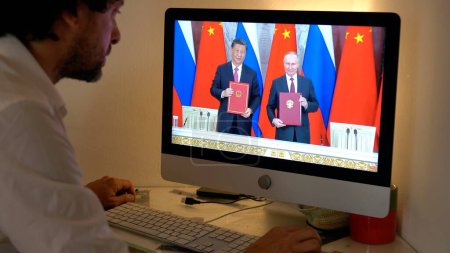 Foto de Europa, Milán 2023 - Ver las noticias de televisión en un ordenador portátil sobre la guerra entre Rusia y Ucrania - Vladimir Putin y Xi Jinping reunión China y Rusia - Imagen libre de derechos