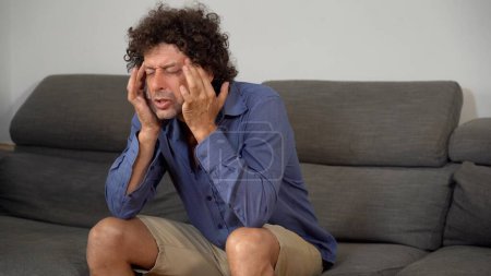 Téléchargez les photos : Homme avec un mal de tête sur le canapé - en image libre de droit