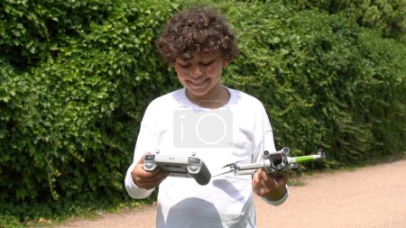 Téléchargez les photos : Garçon enfant 9 ans jouer et voler avec un drone - rêver de voler dans l'enfance - apprendre aux enfants à utiliser un drone en toute sécurité avec licence - en image libre de droit