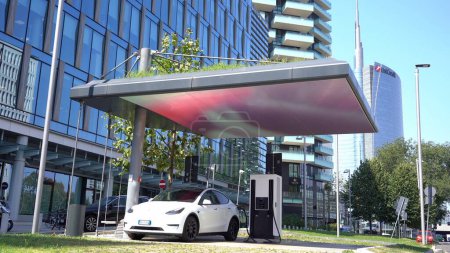 Photo for Europe, Italy, Milan 08-25-23 - Tesla electric car is charging the battery in a modern electricity recharging station in downtown of the city - new new sustainable electric mobility - global warming - Royalty Free Image