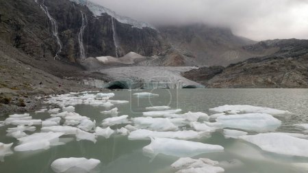 Téléchargez les photos : Vue depuis le drone de Fellaria fonte des glaciers larguant des icebergs - morceaux de glace que nous flottons dans le lac en raison du dégel à haute température - Réchauffement climatique et changement climatique en Europe, Italie Alpes - en image libre de droit
