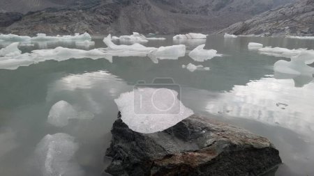 Foto de Fellaria derretimiento glaciar caída de icebergs - trozos de hielo que flotan en el lago debido al deshielo de alta temperatura - Calentamiento global y el cambio climático en Europa, Italia Alpes - Imagen libre de derechos
