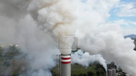 Photo for Atmospheric pollution and emission of combustion fume gas released into the air from a factory - chimney emits fine dust smog - Climate change and global warming concept - flue drone aerial view - Royalty Free Image