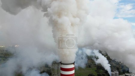 Foto de Contaminación atmosférica y emisión de gases de humo de combustión liberados al aire desde una fábrica - chimenea emite humo de polvo fino - Cambio climático y concepto de calentamiento global - visión aérea de drones de combustión - Imagen libre de derechos