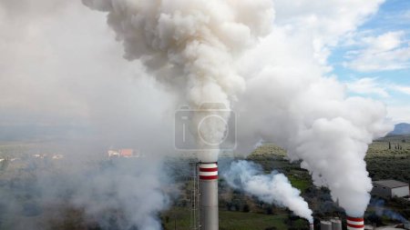 Téléchargez les photos : Pollution atmosphérique et émission de gaz de combustion rejetés dans l'air par une usine - cheminée émet du smog fin de poussière - Changement climatique et réchauffement climatique - drone de fumée vue aérienne - en image libre de droit