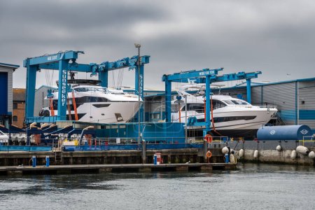 Téléchargez les photos : 2 différents modèles de yachts tenus sur des portiques extérieurs à l'usine principale de Sunseeker à Poole quai, dorset - en image libre de droit