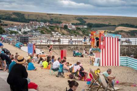 Foto de Children and adilts watching a traditional Punch and Judy show on the sandy beach at Swanage Dorset - Imagen libre de derechos