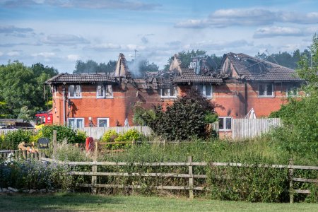 Photo for A 4 house terraced row after a house fire with roofs burned away and smoke and steam still emerging as Dorset and Wiltshire fire service continue to damp down - Royalty Free Image