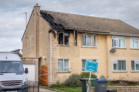 Photo for Bradford on Avon, Wiltshire, UK, Sep 15 2022. A semi detached house the morning after a fire. There is a for sale sign in the garden and visible damage to an upstairs window and the roof. - Royalty Free Image
