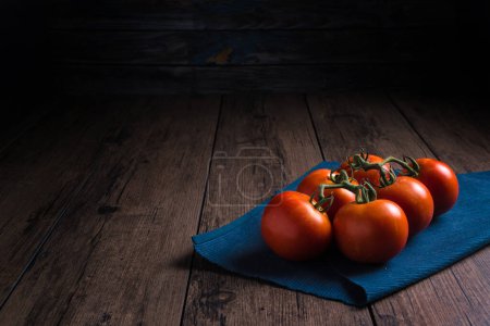Foto de Tomates frescos colocados en un plato de piedra negro colocado sobre una mesa de madera. - Imagen libre de derechos