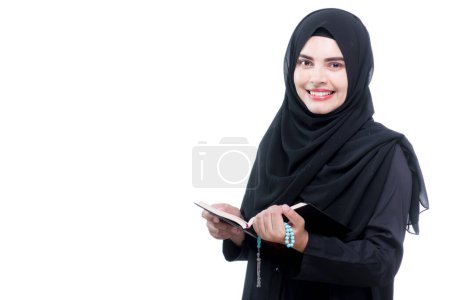 Photo for Portrait Asian Muslim woman standing and reading the Quran and appreciates and faith The Holy Al Quran with written Arabic calligraphy meaning of Al Quran, Arabic word translation : The Holy Al Quran. - Royalty Free Image