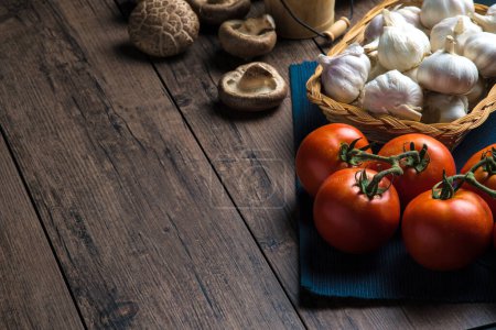 Foto de Cerrar Ingredientes para cocinar ingredientes como tomates, ajo y champiñones colocados en una mesa de madera, con espacio para copiar. - Imagen libre de derechos