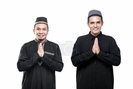 Foto de Dos hombres musulmanes asiáticos guapos de pie, hola, saludo con una cara sonriente, sobre fondo blanco. - Imagen libre de derechos