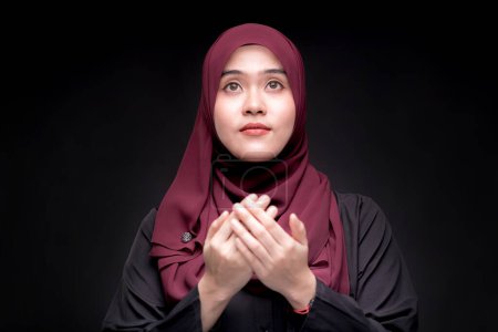 Foto de Retrato Mujer musulmana asiática está orando por la oración con fe y determinación. sobre fondo negro. - Imagen libre de derechos