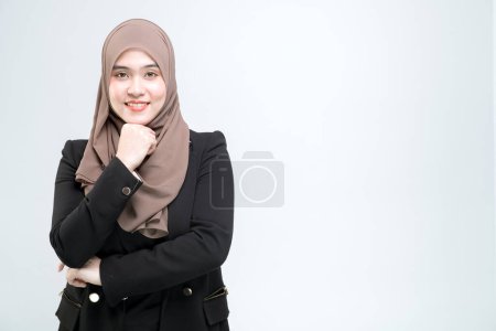 Foto de Un oficinista para una mujer musulmana asiática está de pie con los brazos cruzados con una cara feliz y un compromiso de trabajo, sobre un fondo blanco. - Imagen libre de derechos