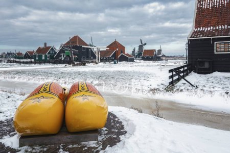 Foto de Zaandam, Países Bajos, 10 de febrero de 2021: El símbolo de los Países Bajos es un klomp y un molino de viento sobre el telón de fondo de un paisaje invernal en el pequeño pueblo de Zaanse Schans. - Imagen libre de derechos
