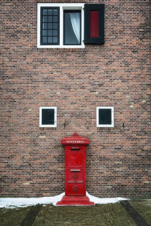 Téléchargez les photos : Zaandam, Netherlands, February 10, 2021:Old red mailbox in front of brick wall in Zaanse Schans, Netherlands. - en image libre de droit