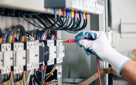 Elektriker-Ingenieur-Arbeitsprüfer misst Spannung und Strom der Stromleitung in der Schaltschranksteuerung. 