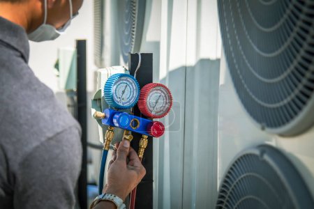 Photo for Air conditioning, HVAC service technician using gauges to check refrigerant and add refrigerant. - Royalty Free Image