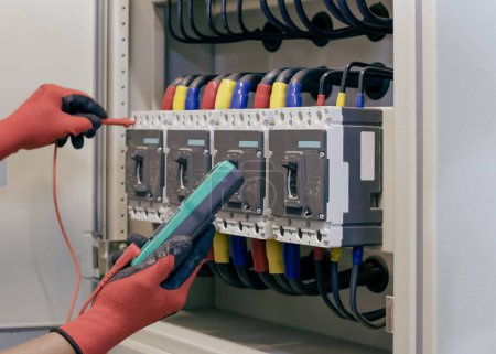 Foto de Ingeniero eléctrico prueba el funcionamiento del armario de control eléctrico sobre una base regular para el mantenimiento. - Imagen libre de derechos