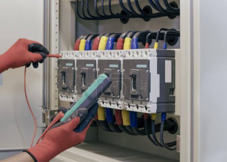 Ingeniero eléctrico prueba el funcionamiento del armario de control eléctrico sobre una base regular para el mantenimiento.