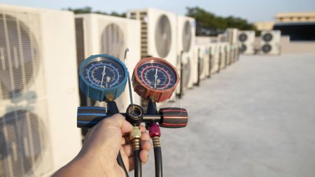 Photo for Air conditioning, HVAC service technician using gauges to check refrigerant and add refrigerant. - Royalty Free Image