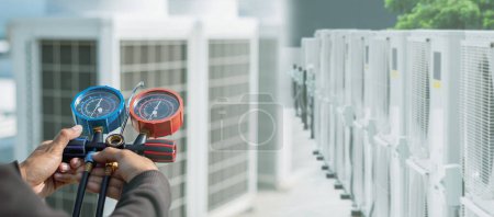 Klimaanlage, Klimatechniker mit Manometern, um Kältemittel zu überprüfen und Kältemittel hinzuzufügen.