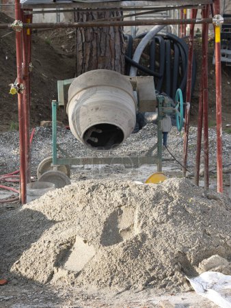 portable concrete mixer or cement mixer used to combine cement , sand, and water to form concrete , in a  construction site
