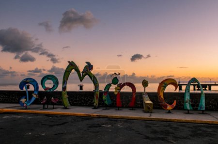 Téléchargez les photos : Un panneau touristique sur le front de mer au coucher du soleil à Roseau, Dominique - en image libre de droit