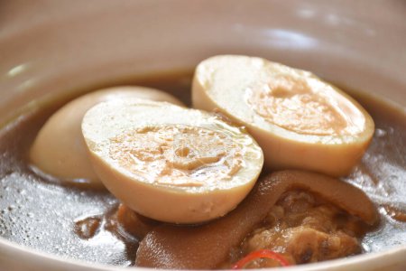 Photo for Boiled half cut egg with fat pork leg in herb brown soup on bowl - Royalty Free Image