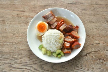 roasted barbecue and crispy pork slice topping plain rice with boiled egg dressing sweet red gravy sauce on plate 