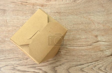 noodles packaged in hard brown paper box for take home on table