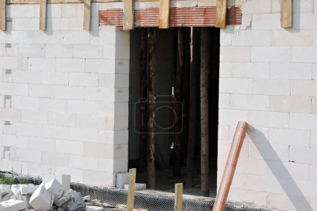 Foto de Una abertura áspera de la ventana, dinteles de ladrillo reforzado, paredes hechas de hormigón aireado en autoclave y elementos de madera dentro de una casa en construcción - Imagen libre de derechos
