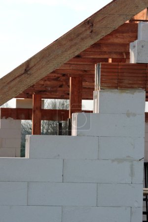 Foto de A timber roof truss in a house under construction, walls made of autoclaved aerated concrete blocks, a reinforced brick lintel, blue sky in the background - Imagen libre de derechos