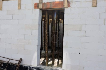 Foto de Una abertura áspera de la puerta, dinteles de ladrillo reforzado, paredes de hormigón aireado en autoclave y elementos de madera dentro de una casa en construcción - Imagen libre de derechos