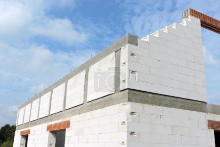 Foto de A reinforced concrete beam and reinforced concrete columns, reinforced brick lintels, a rough door and windows openings, a gable wall, walls made of aac blocks, blue sky in the background - Imagen libre de derechos