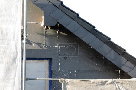 Photo for A wall of a house covered with EPS graphite polystyrene boards for thermal insulation, a window covered with a protective film, a scaffolding - Royalty Free Image