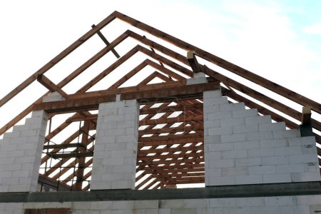 Ein "A" -Fachwerk-Dachstuhl in einem im Bau befindlichen Haus von unten gesehen, Wände aus Aac-Blöcken, eine grobe Fensteröffnung, ein verstärkter Klinkersturz, ein Gerüst