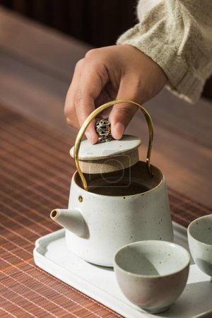 Photo for Image of tea set, person making Asian-style tea, tea cup and teapot - Royalty Free Image