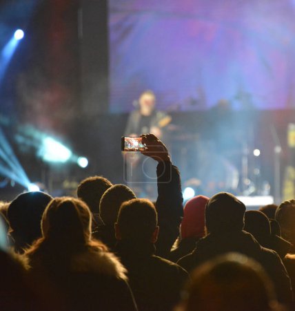 Foto de Cabezas y manos de una gente que graba el escenario con teléfonos móviles durante un concierto de rock - Imagen libre de derechos