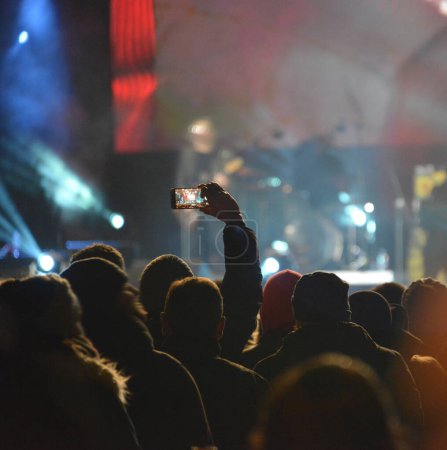Foto de Cabezas y manos de una gente que graba el escenario con teléfonos móviles durante un concierto de rock - Imagen libre de derechos