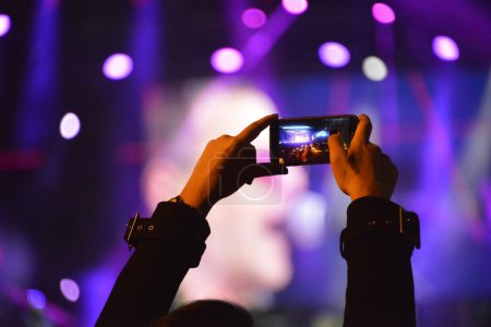 Foto de Manos de la chica que graba el escenario con un teléfono móvil durante un concierto - Imagen libre de derechos