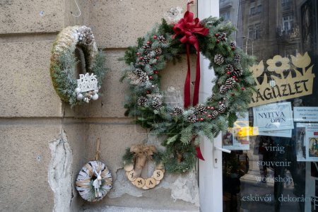 Foto de Budapest, Hungría - 1 de diciembre de 2022: Decoraciones navideñas en una pared junto a la entrada de una tienda en una calle de Budapest. - Imagen libre de derechos