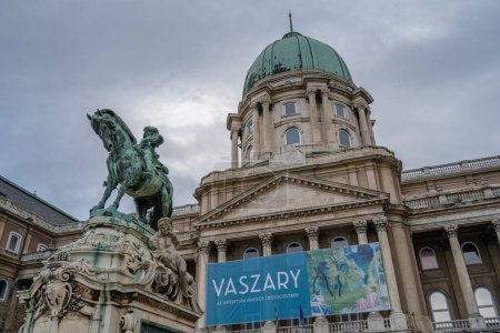 Foto de Budapest, Hungría - 26 de noviembre de 2022: El edificio de la galería nacional húngara en un día nublado de invierno, con un signo de la exposición del artista Vaszary. - Imagen libre de derechos