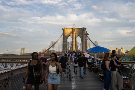 Foto de Nueva York, Estados Unidos - 23 de julio de 2023: Turistas y vendedores en el puente de Brooklyn al atardecer. - Imagen libre de derechos