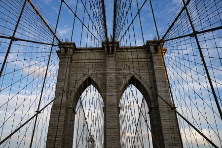 Foto de Los elementos estructurales del puente de Brooklyn, cables de acero y pilares de piedra, en un día parcialmente nublado. - Imagen libre de derechos