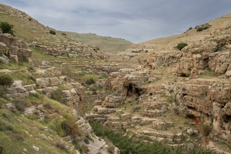 Eine Landschaft aus Klippen und Höhlen am Ufer des Flusses Prat in den Hügeln der Wüste Judäa, Israel.