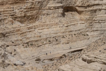 Hikers on a path below the formidable cliffs of Ein Avdat canyon in the Negev desert, Israel.