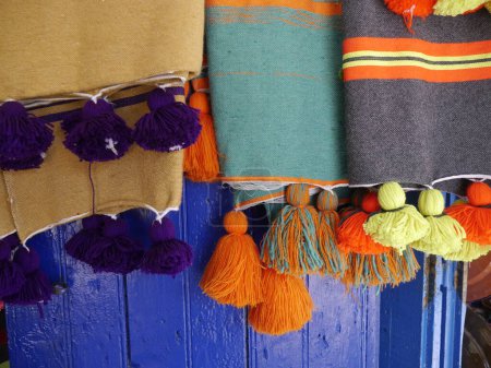 Close up of handmade Moroccan cloth throws in bright traditional patterns and vivid colours with tassels on sale as souvenirs