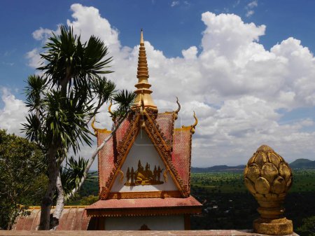 Detail of ornate Buddhist temple with golden decoration at Phnom Sampeau, Battambang, Cambodia with beautiful sky for copy space. High quality photo